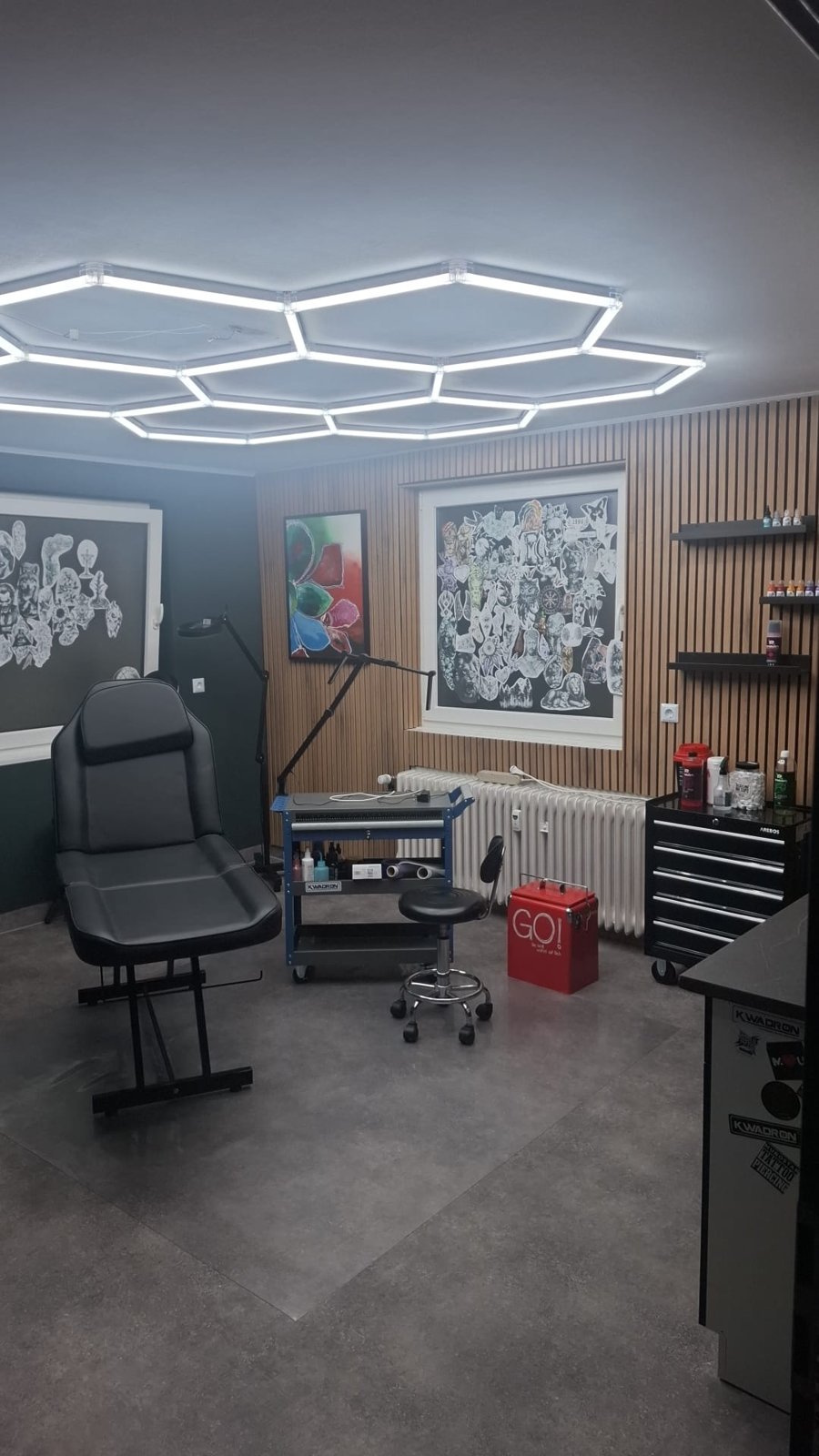 Arbeitsplatz im Studio: Liege, Wabenlicht an der Decke, Holzwand mit Flash-Motiven